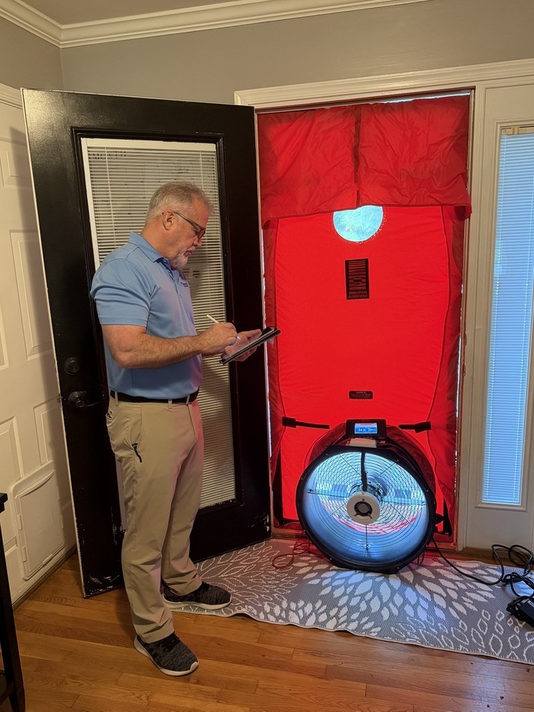 A technician conducts a blower door test in a home, measuring air leaks.